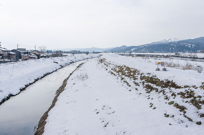 雪が積もった小矢部川の堤防
